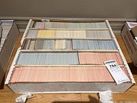 Large white storage box filled with rows of baseball cards organized by color-coded backs in packs or sleeves.