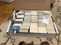Photo of a cardboard box filled with neatly stacked baseball cards, showing the large quantity and variety.