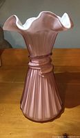 Front view of pink Fenton art glass vase with ruffled top and ribbed wheat pattern.