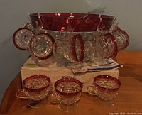 Full view of punch bowl set including bowl, ladle, and twelve footed glasses arranged over original box with invoice visible.