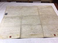 Full view of large handwritten land deed on parchment showing text and wax seals