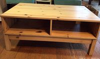 Front view of the wooden coffee table showing two open storage compartments beneath the tabletop.
