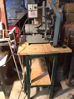 Overall view of bench-top belt sander on metal stand with wooden top and lower shelf