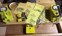 Overview of two yellow radiation meters, manuals, tubes and accessories