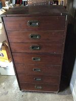 Tall solid wood cabinet front view showing six drawers and brass handle hardware