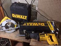 Overall view of the DeWalt circular saw, reciprocating saw, and their cases on the bench