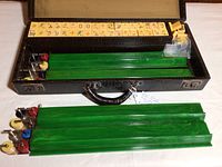 Open case showing tiles arranged in lid, green racks removed, scoring counters attached to racks and dice in plastic bag