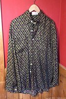 Silk shirt with geometric pattern hung on hanger against red wall