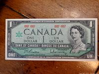 Two vintage Canadian one dollar banknotes commemorating the Canadian Confederation Centennial, dated 1867-1967. Each note features Queen Elizabeth II and bilingual English-French text indicating "One Dollar" and "Un Dollar."