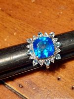 Front-facing image of the ring showing the vibrant cushion-cut blue Caribbean quartz center stone surrounded by clear multi-shaped gemstones on a platinum-plated sterling silver band.