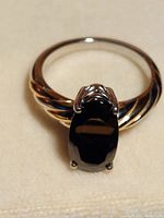 Front view of the Indian elite shungite ring showing the oval black gemstone and twisted band design in rose gold and platinum plating over sterling silver.