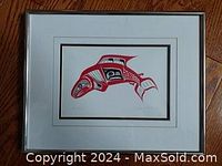 Front view of framed salmon art print showing traditional Native design in red and black with white double mat and chrome frame.