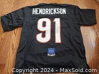 Back view of black NFL jersey, size XL, signed by Trey Hendrickson, number 91 with name on back.