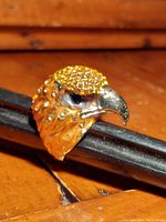 Close-up side view of the gold-tone falcon head ring with yellow Austrian crystals on top, showing detailed features and crystals.