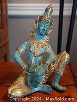 Front view of the vintage solid cast musical Buddha statue showing intricate golden bronzed detailing and blue-green patina.