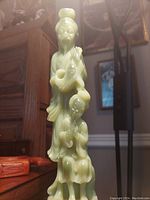 Full front view of tall pale green carved duo sculpture on hexagonal wood base