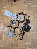 Photo showing multiple assorted cables including HDMI, coaxial, extension cords and connectors laid on a wood parquet floor