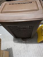 Top side view of the brown plastic laundry hamper, showing vented lattice sides and hinged lid with handle.