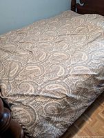 Comforter fully spread on a queen bed, showing the paisley pattern and some wrinkles on the fabric.