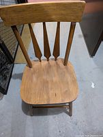 Wooden chair with contoured seat and vertical slatted backrest in light brown wood.