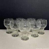 Front view of all eight textured clear glacier pattern Indiana Glass goblets arranged in two rows.