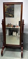 Front view of full-length cheval mirror on wheels showing rectangular mahogany wood frame and mirror surface.
