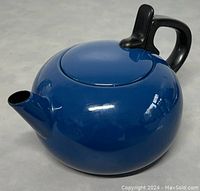 Front angle view of the blue enamel stove top kettle showing its round body, short spout, and black handle.