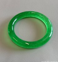 Close-up photo of the fully round green jade bangle showing its vibrant color and polished surface.