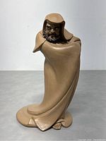 Front view of light brown ceramic statue depicting a hooded bearded figure in flowing robes
