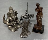 Overview photo showing all four items in the lot including Ganesha statue, Venus de Milo statue, knight on horse figurine, and bird figurine.