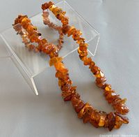 Amber necklace displayed with chips of varying sizes and colors from honey to dark amber, showing natural inclusions and minor wear.