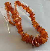 Full view of amber necklace laid out with close visibility of amber hues and shapes.