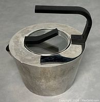 Top view of stainless steel modern tea kettle showing the glass lid insert and black handle.