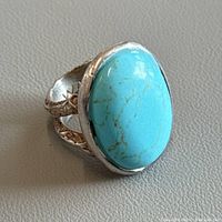Front view of vintage turquoise stone and silver ring showing the oval turquoise and engraved band details.