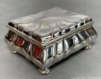 Front side view of the silver plated Art Nouveau dresser box with its molded decorative design and ball feet.