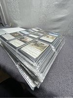 Side angle view showing multiple pages of Magic The Gathering cards in plastic sleeves inside a large binder, cards are sleeved individually.