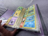 Photo showing large stack of Pokémon cards in plastic binder sleeves, including energy and Pokémon cards.
