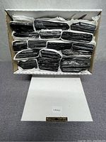 Box containing multiple black tourmaline stones packed in tissue paper, showing overall quantity and condition.