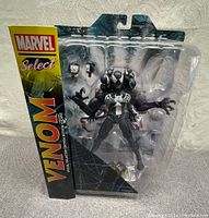 Front view of Venom action figure in packaging showing multi-headed figure and interchangeable hands.