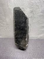 Single large double terminated Smokey Quartz crystal laying on a fabric surface showing full length and natural terminus points.