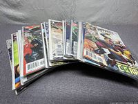Stack of about 14 comic books with visible colorful covers, mostly DC superheroes like Superman and Batman.