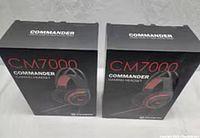 Two boxed Yankyo CM7000 Commander gaming headsets in black and red shown from front angle.