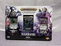 Front view of sealed Warhammer Age of Sigmar Champions Warband Pack Series 2 box showing the two decks Zarbag's Gitz and Eyes of the Nine, and the Savagery booster pack in the middle.