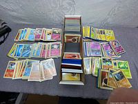 Wide view of all Pokémon cards sorted and sleeved, with a central box holding more cards and energy cards