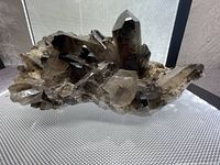 View of the smokey quartz crystal cluster showing multiple large and smaller crystals with natural smoky brown coloration.