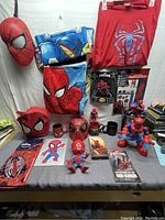 Full display of Spider-Man items including apparel, toys, mugs, and books on a table surface.