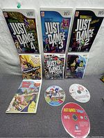 Photo showing seven Wii games including Just Dance titles, Boogie Superstar, Rihanna Dance Party and Mario Party 9 with cases and discs visible