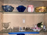 Shelf with four colored glass vases/bowls and multiple smaller glass and ceramic serving pieces.