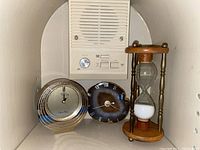 Photo of two clocks and an hourglass on a shelf