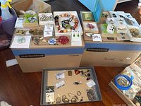 Overview of two white trays and metal tray showing necklaces, earrings, brooches and compact.
